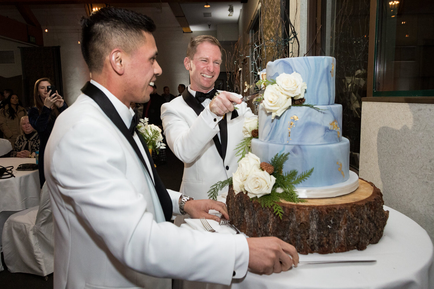 Two grooms cut their blue marbled fondant cake at their reception in the Mountain Room.