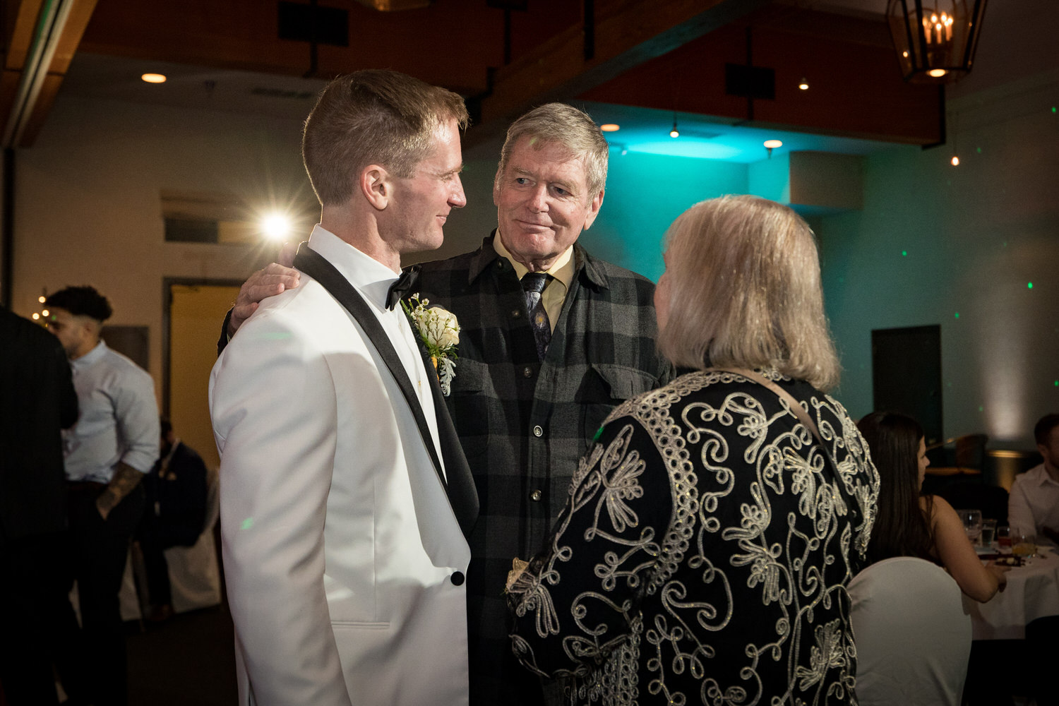 A candid, unposed moment between a groom and his parents captured by wedding photographer Chris Werner.