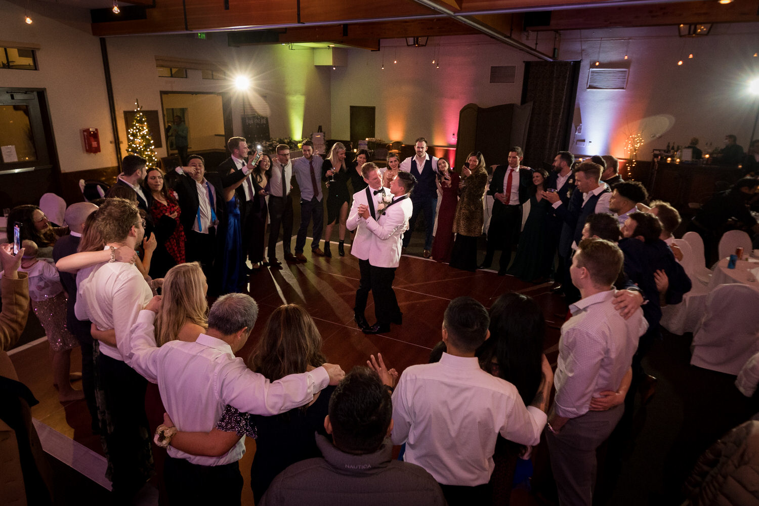 Friends and family surround two grooms on the dance floor at the Mountain Room.