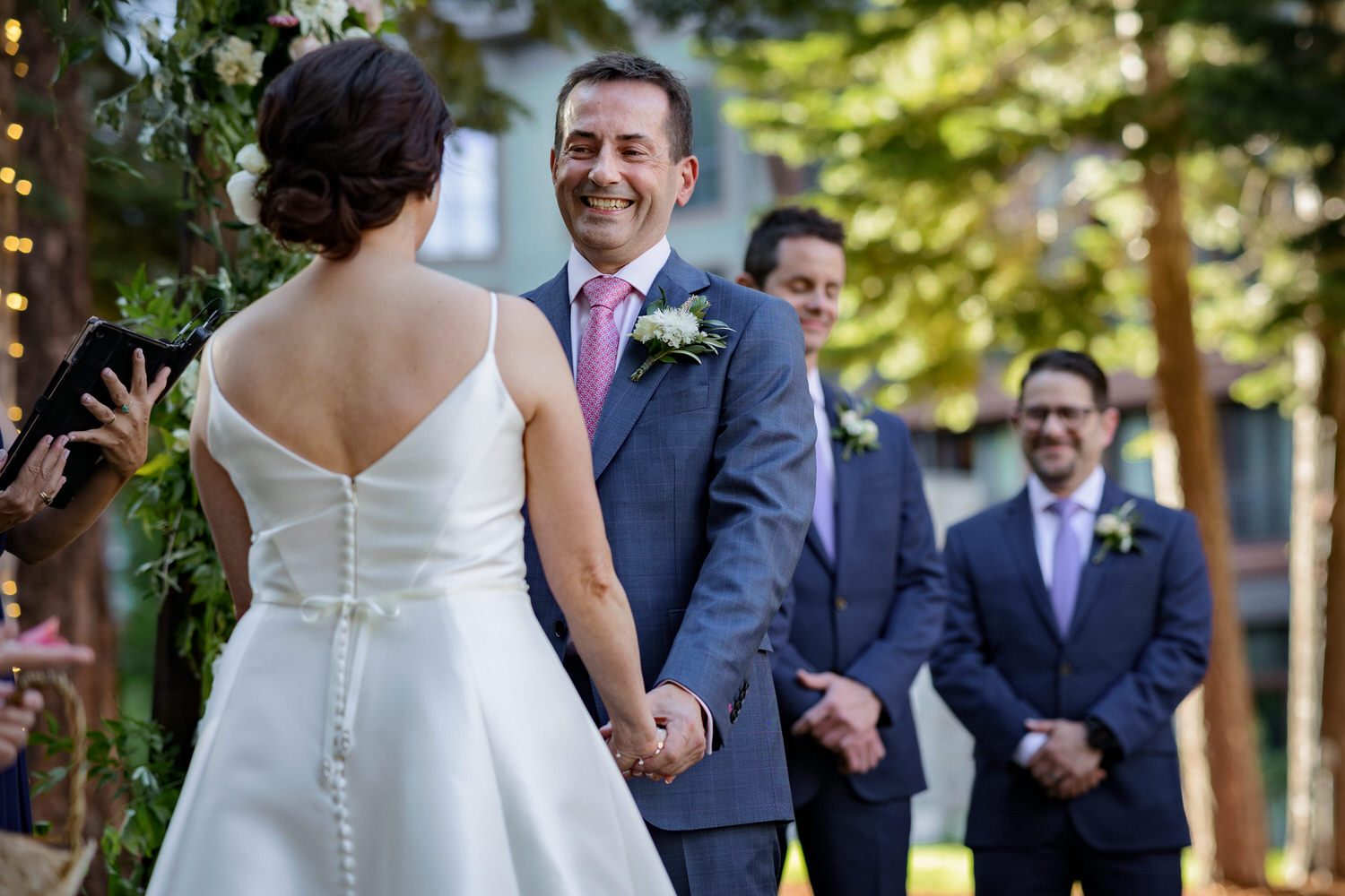 A smiling groom with his bride at The Woods, an outdoor ceremony venue at the Ritz Carlton.