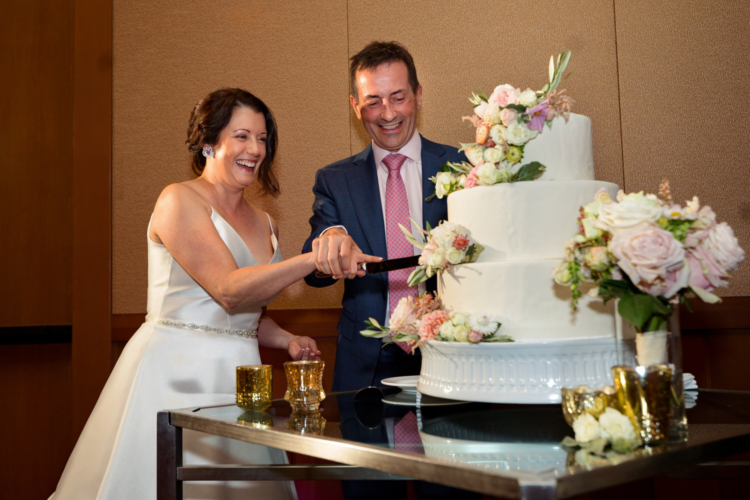 A bride and groom cut their wedding cake in the Ritz Carlton Ballroom.