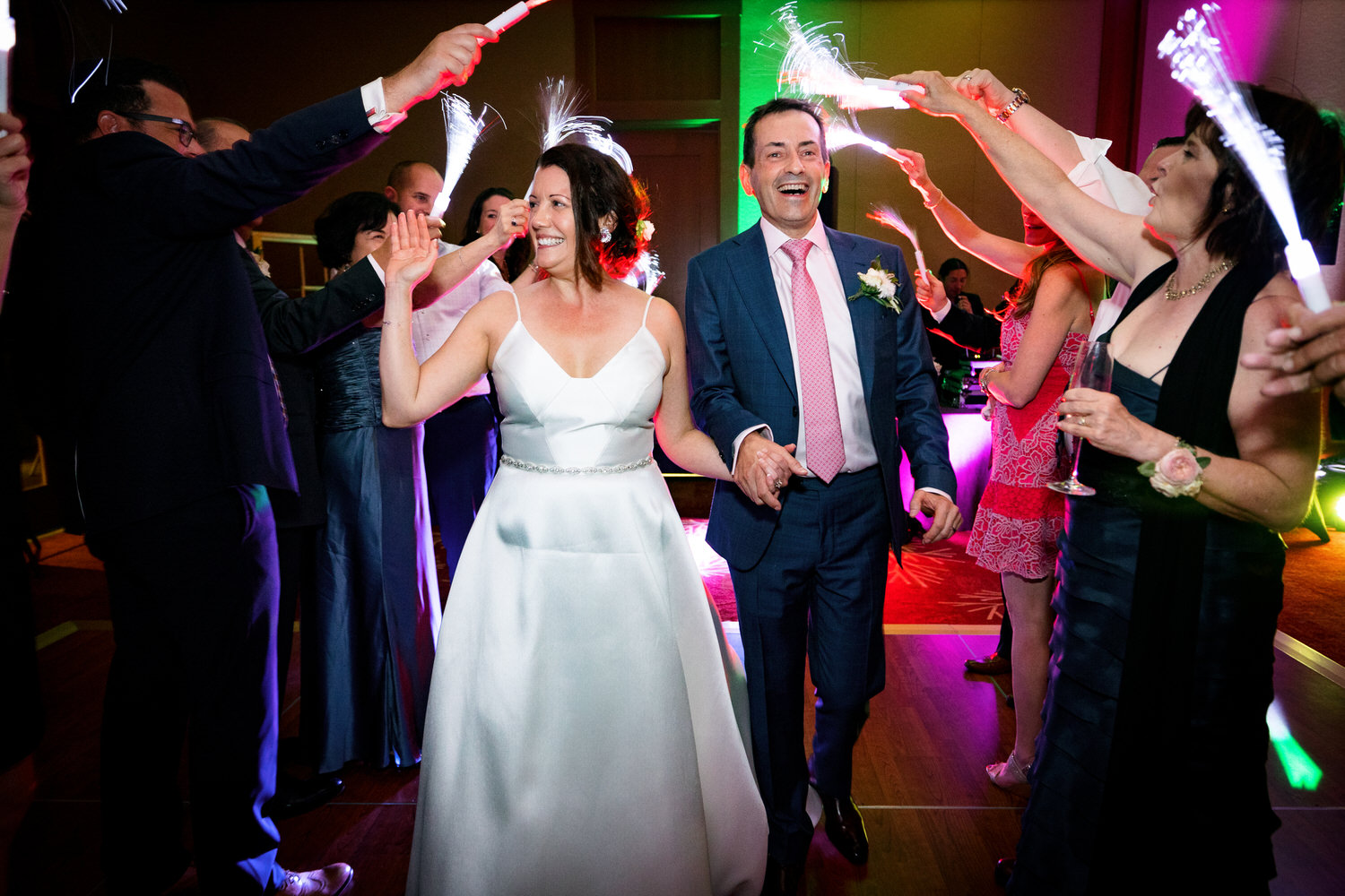 A joyous exit for a bride and groom as wedding guests wave colorful LED fiber wands.