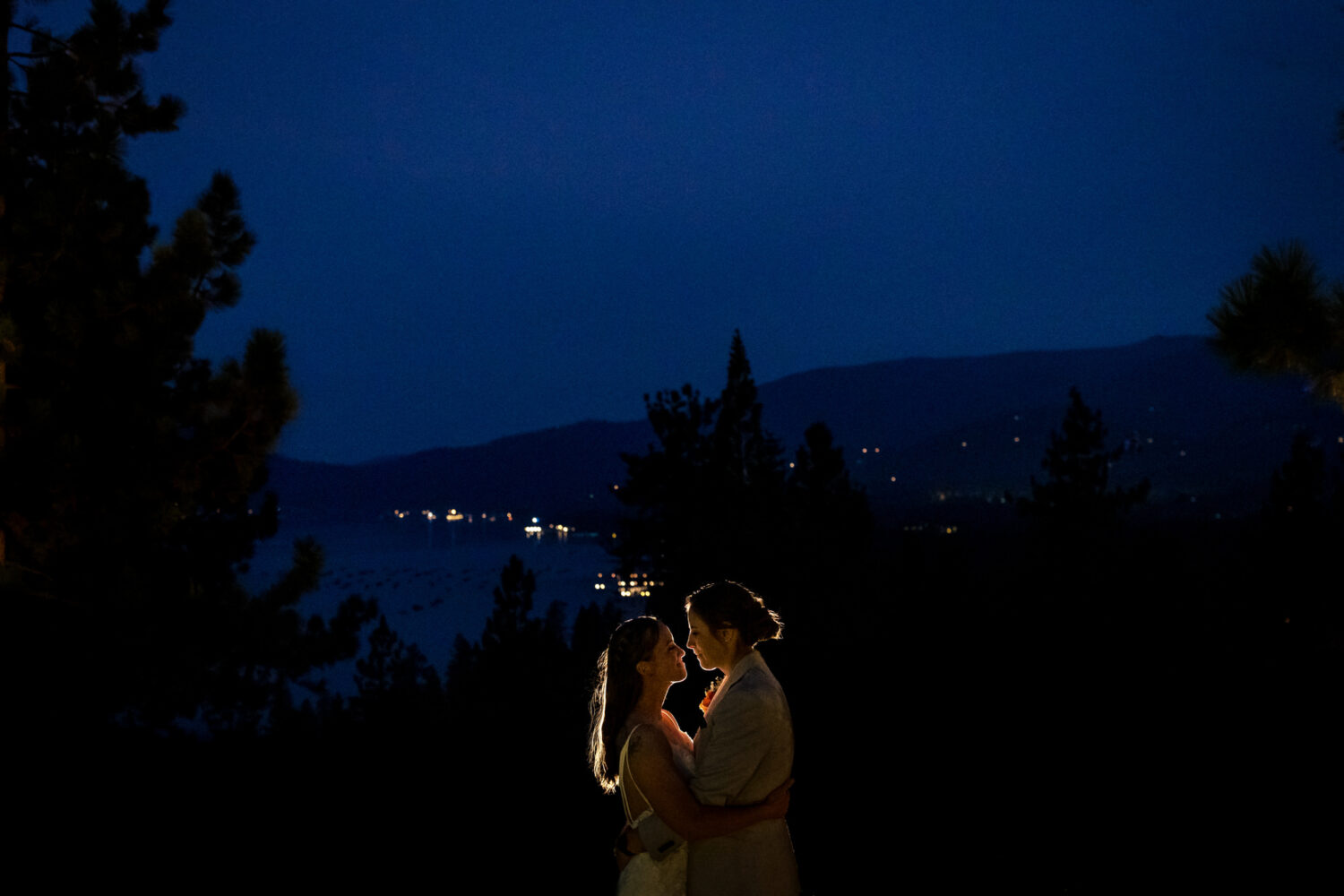 Wide-angle, twilight view of two brides at their Lake Tahoe wedding.