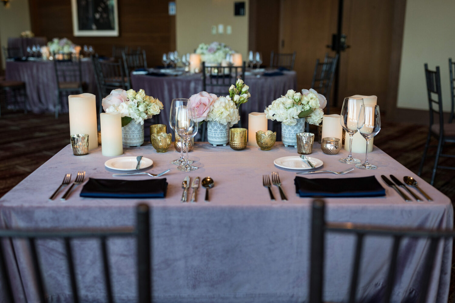 Sweetheart table setting with light purple cloth and blue napkins.