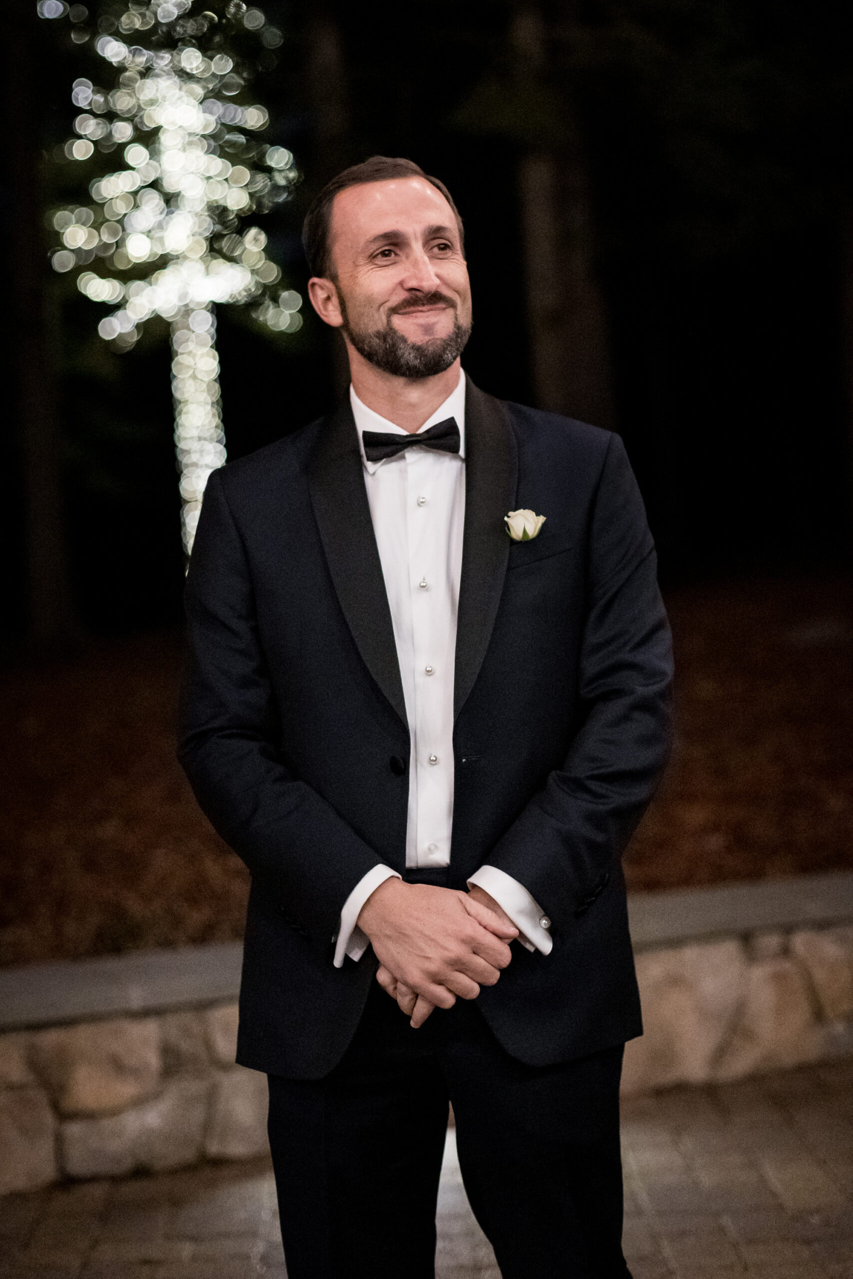 A groom waits for his bride at an outdoor night wedding.