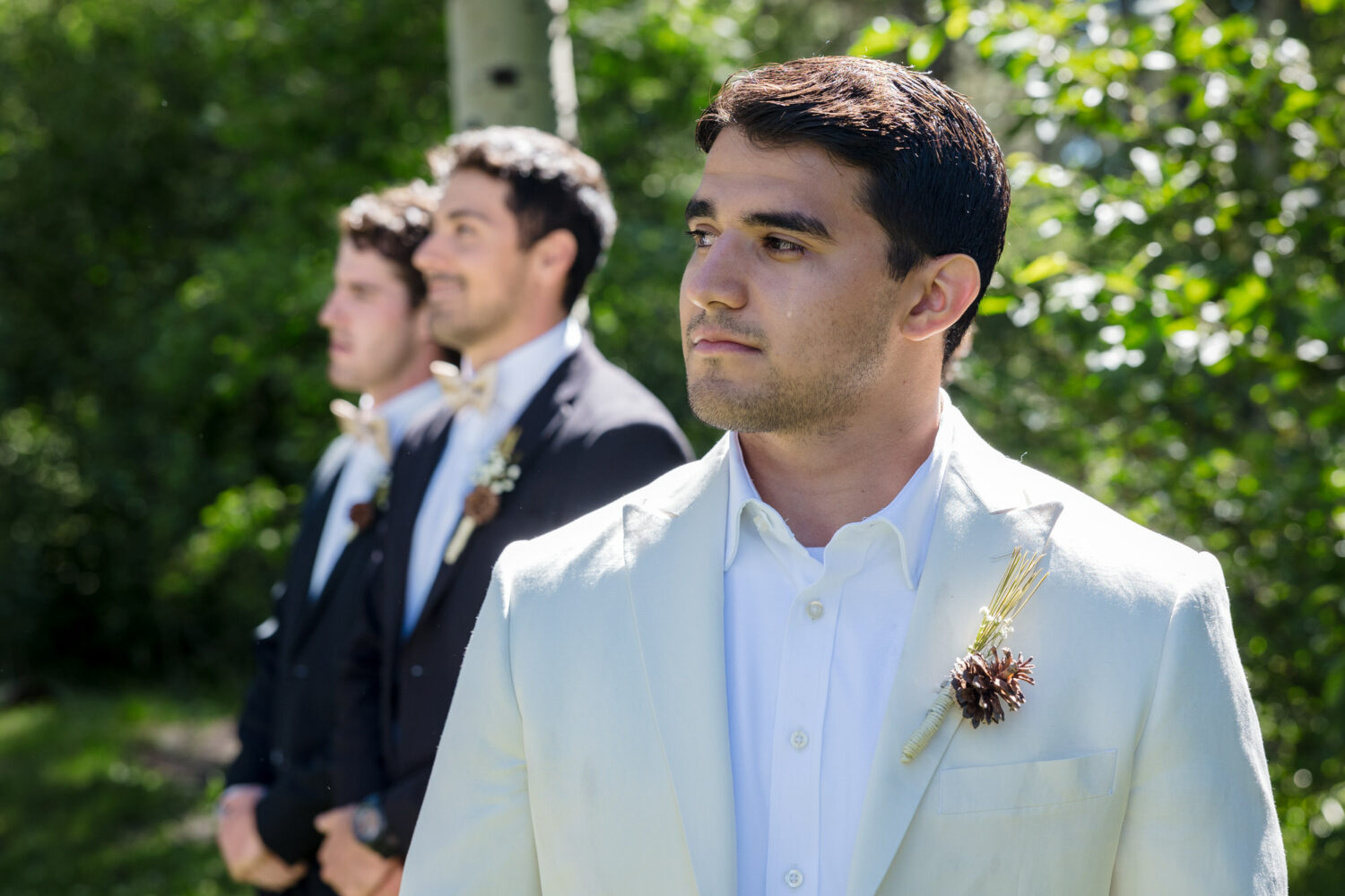 An emotional moment at the altar for a groom wearing a boutonnière with a pine cone and pine needles.