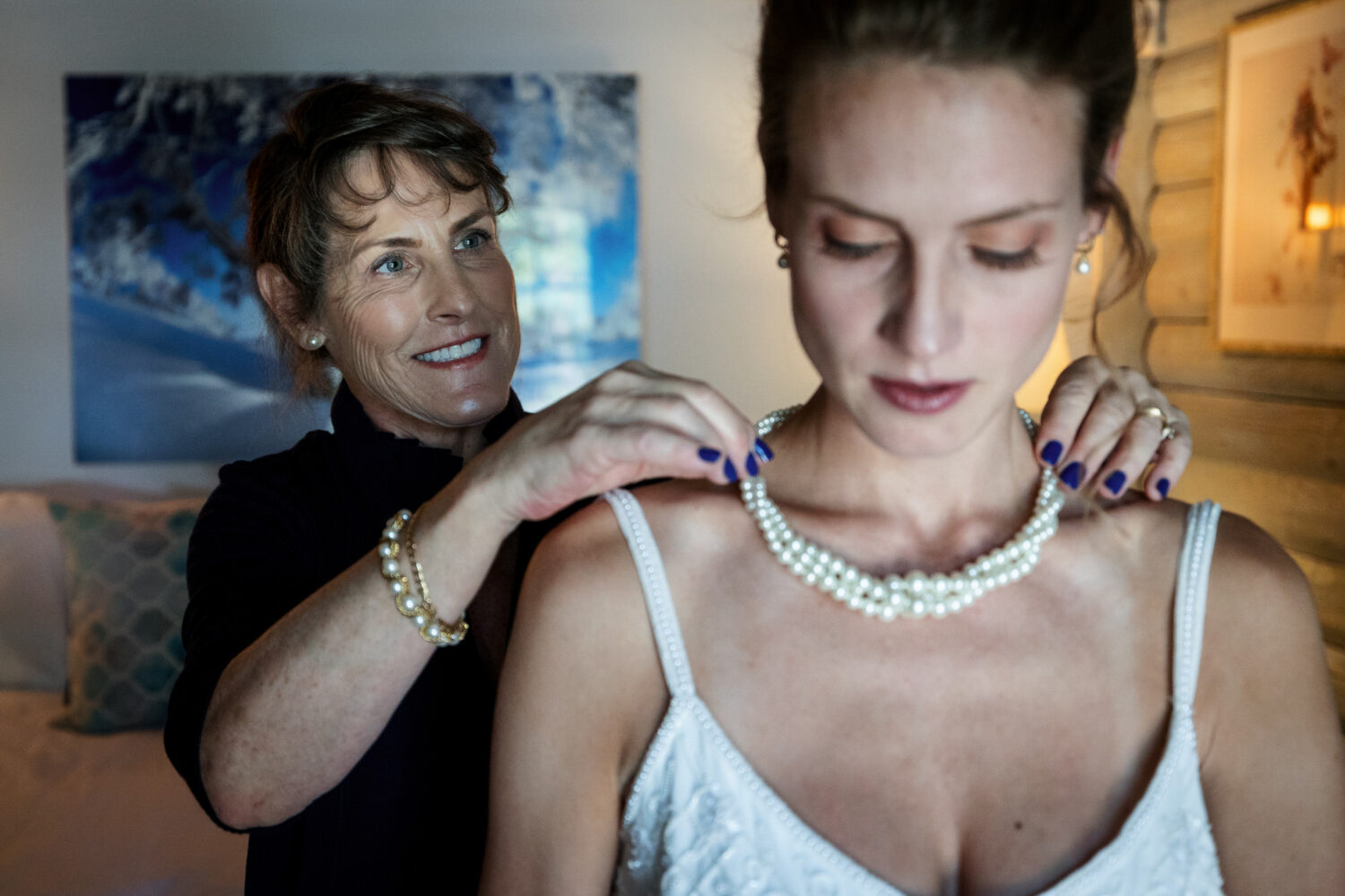 Mother of the bride adjusts the bride's triple strand pearl necklace.