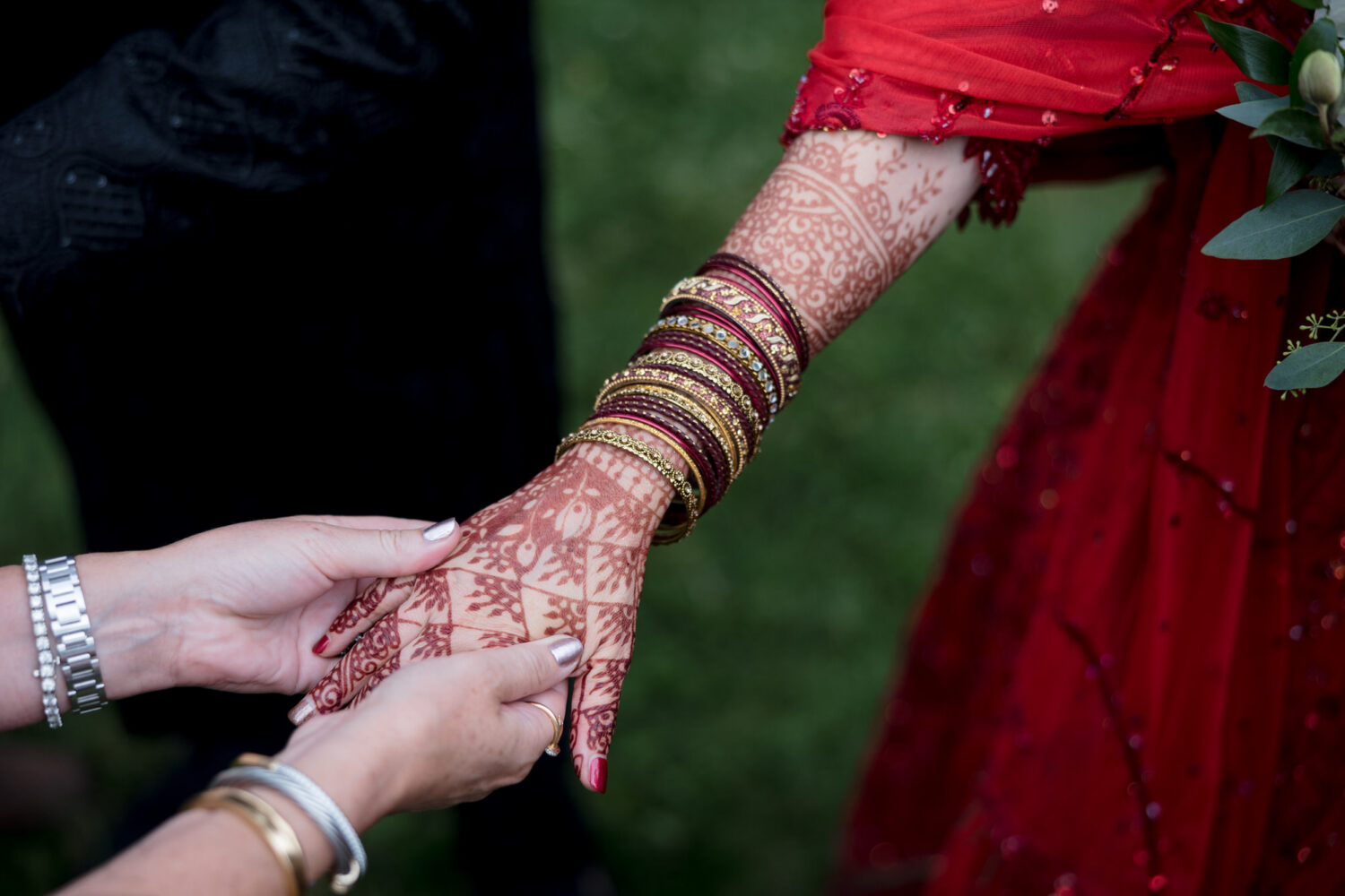 Closeup view of a bride's hands with henna Mehndi and bangles. 