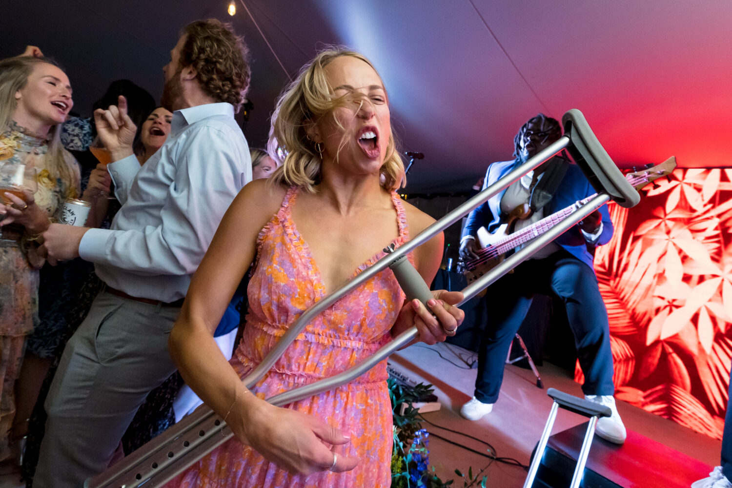 A wedding guest plays the air guitar with her crutch.