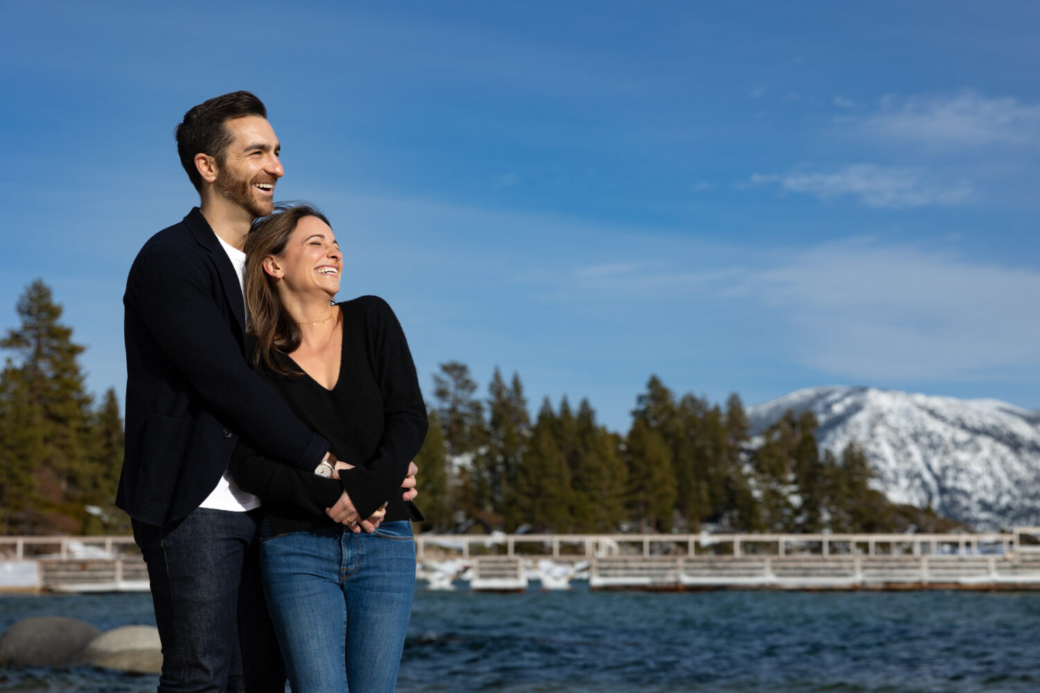 Lake Tahoe engagement session in winter with snowy mountains and blue sky and the background. 