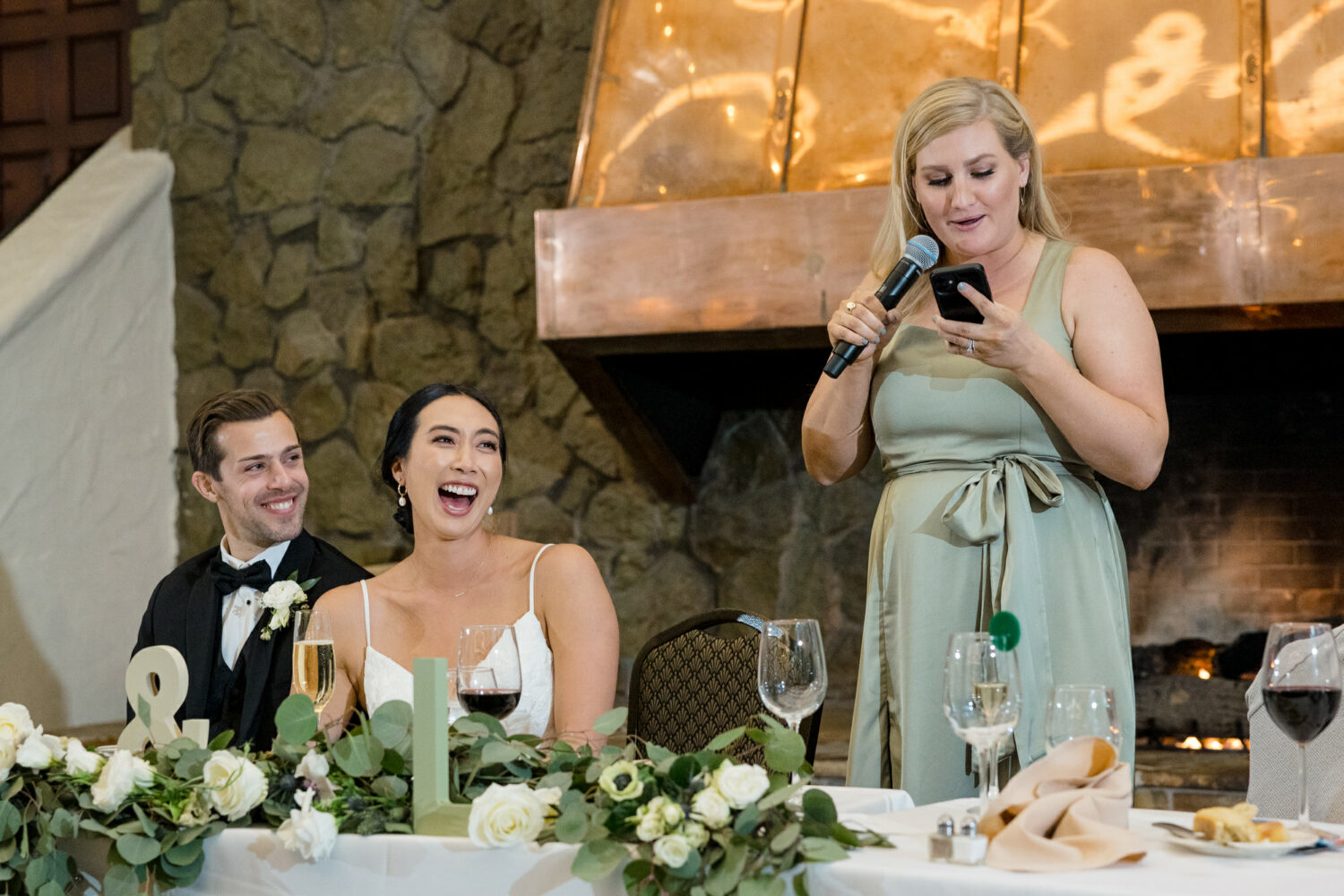 The maid of honor presents a champagne toast in front of the large copper fireplace hood.