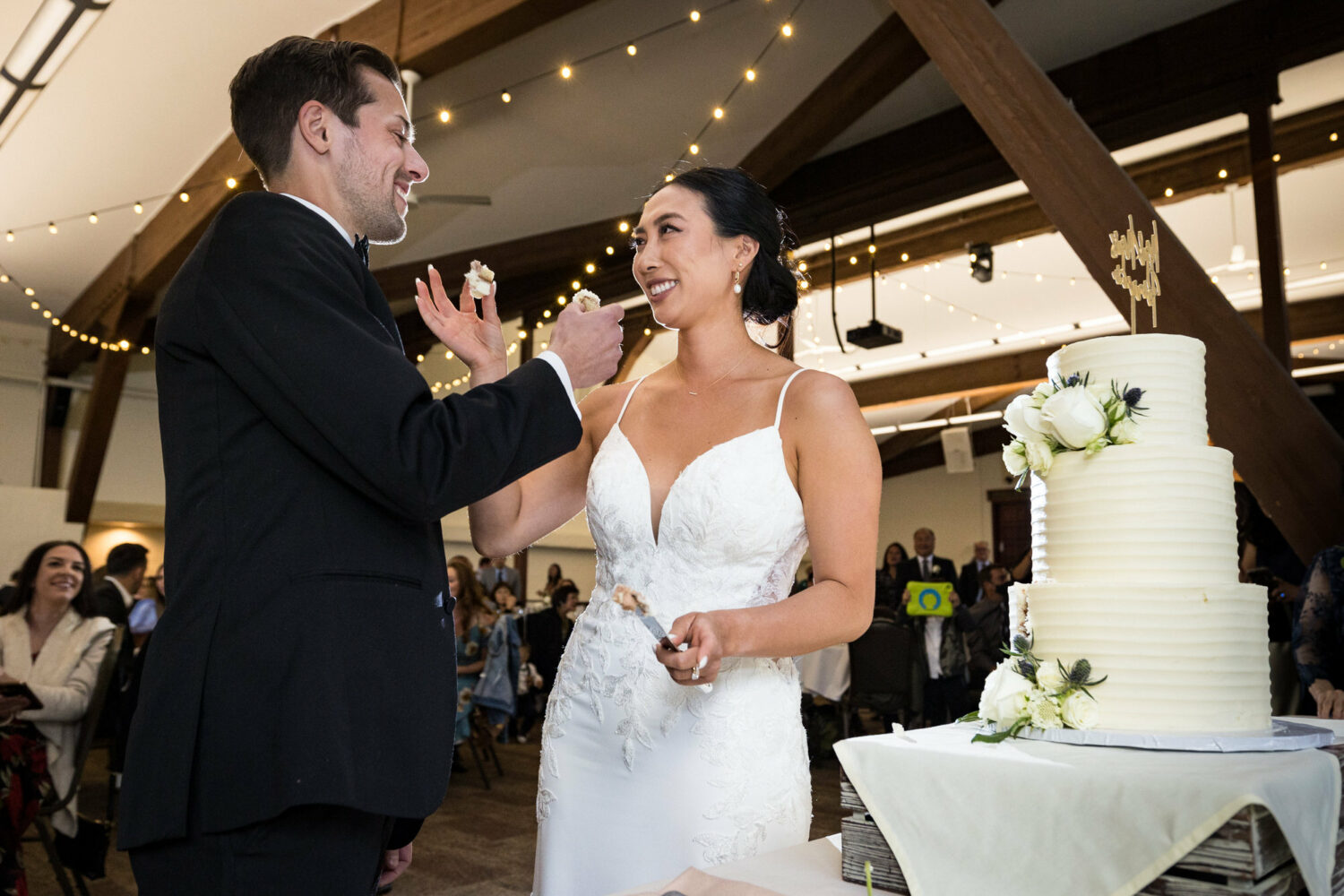 The bride and groom feed each other cake at their Olympic Village Events Center wedding reception.