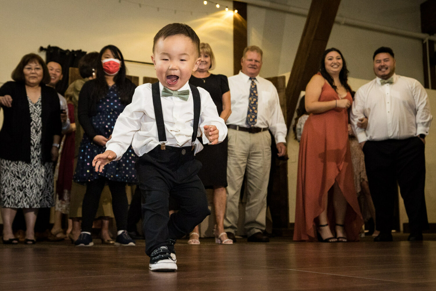 A cute toddler hits the dance floor as wedding guests look on.
