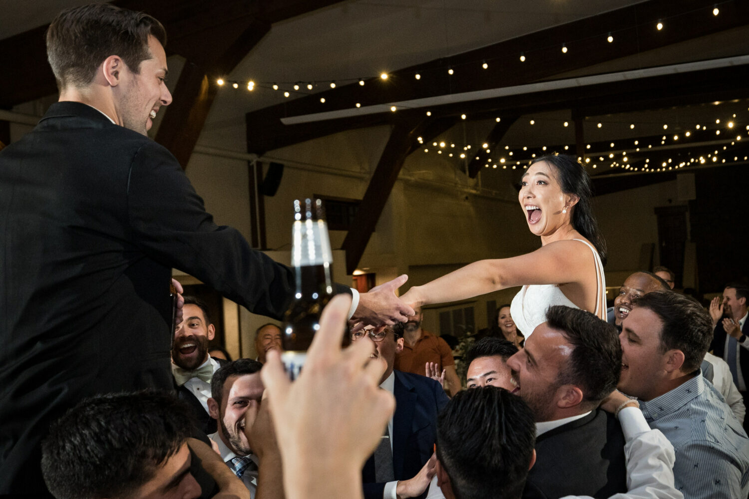 An exciting moment as wedding guests lift the bride and groom on their shoulders.