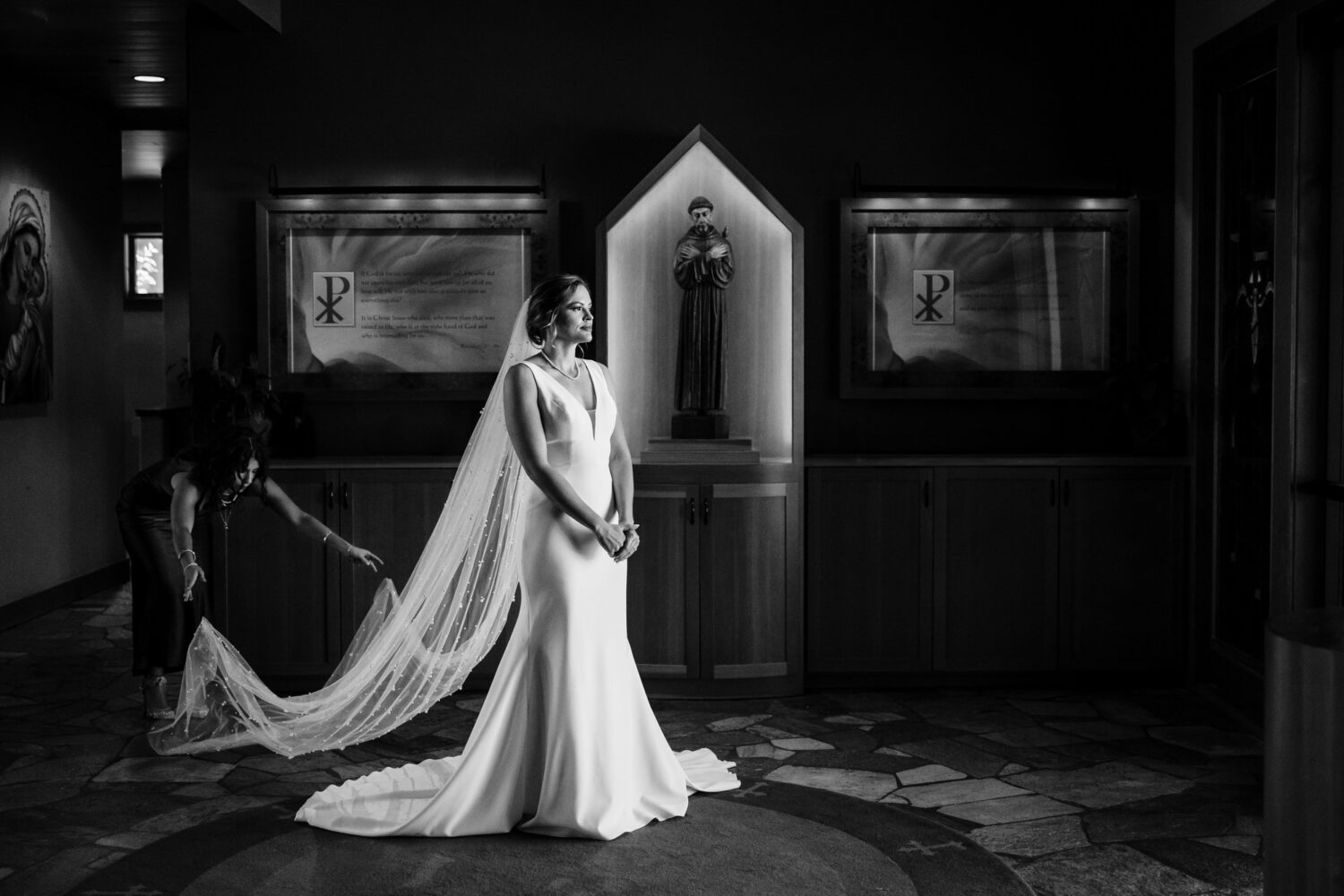 The maid of honor adjusts the bride's long veil before a wedding at St Francis of Assisi in Incline Village.