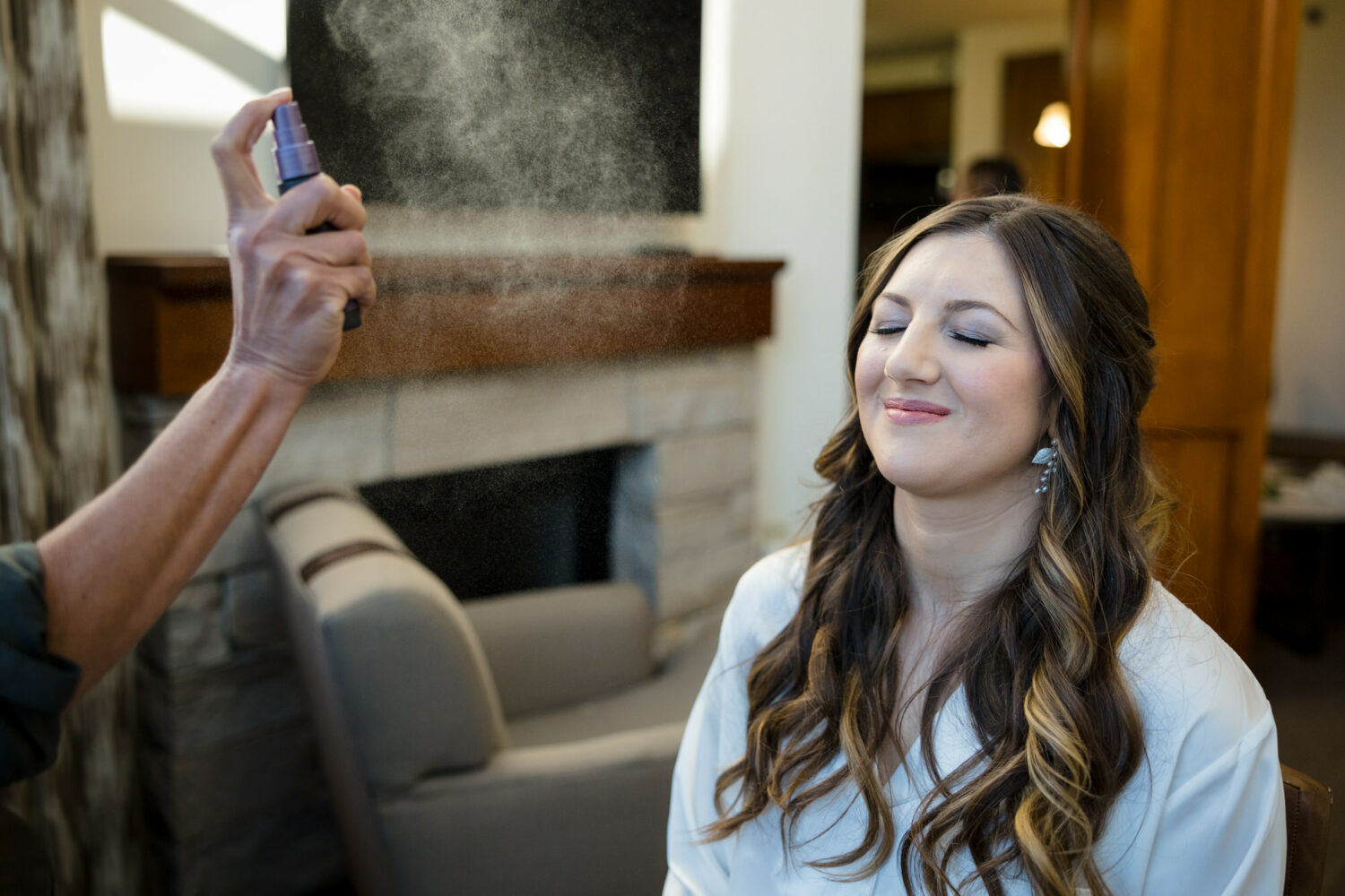 A Lake Tahoe wedding makeup artist applies finishing spray to a bride's face.