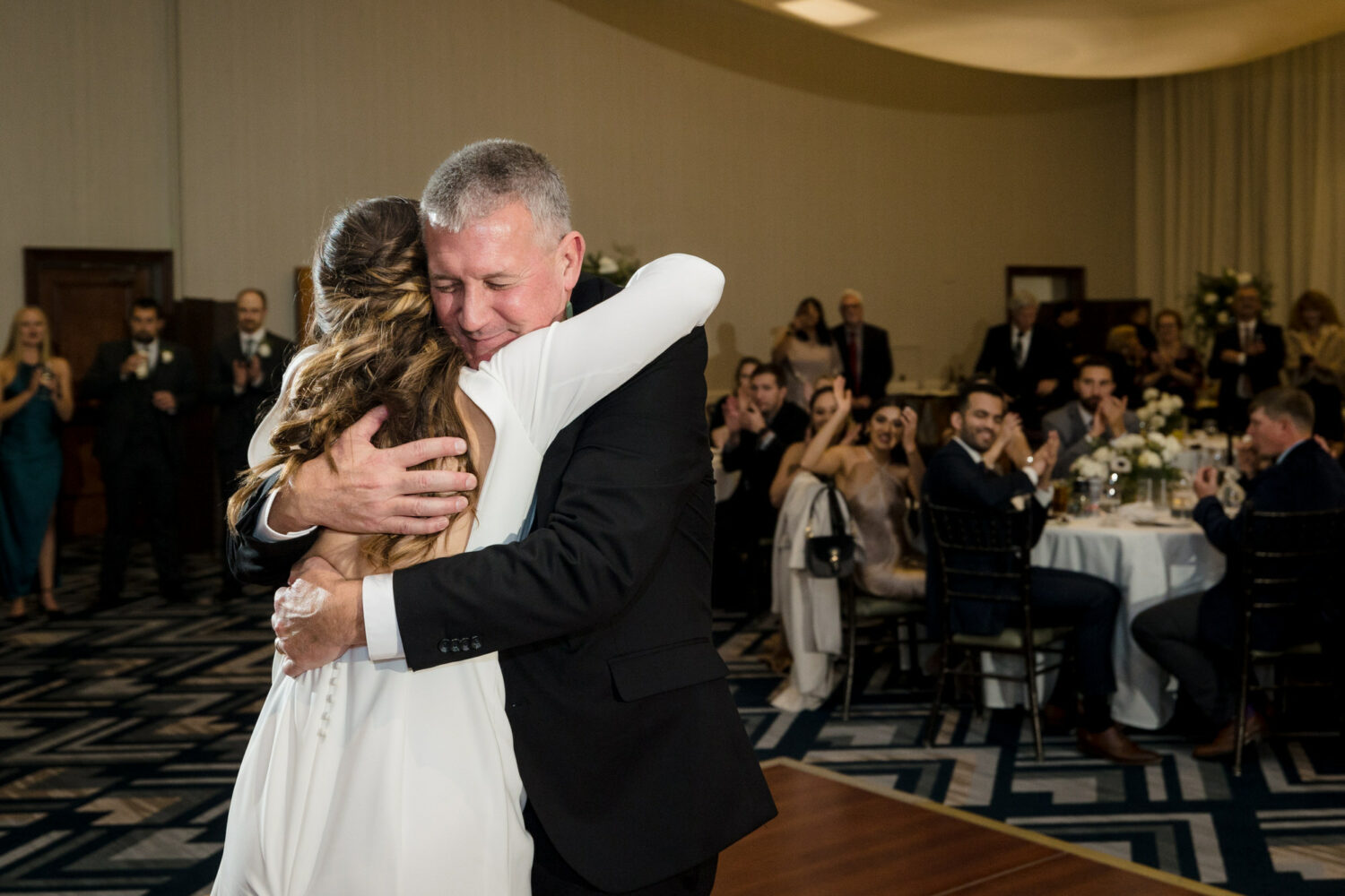 Dancing with the father of the bride at an indoor ballroom reception.