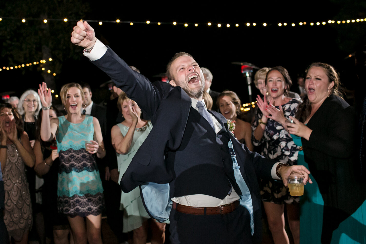 A groom celebrates on the dance floor at a backyard outdoor Lake Tahoe wedding.
