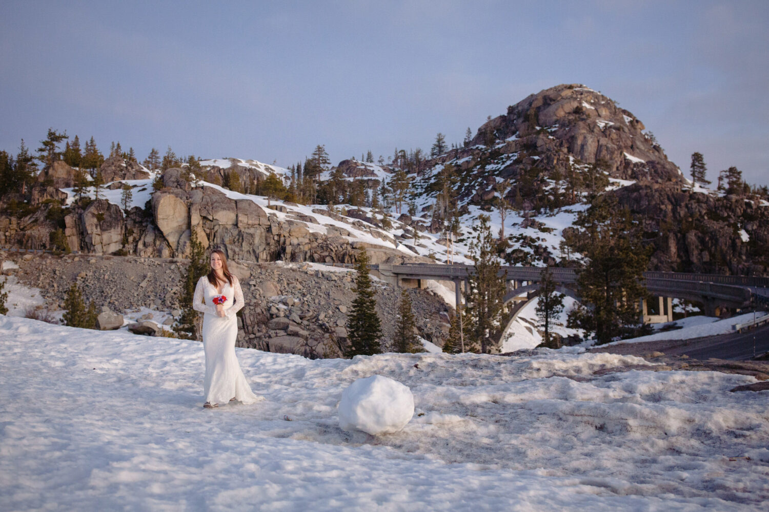 A bride walks across snow to her winter elopement in Tahoe with mountains visible in the background.